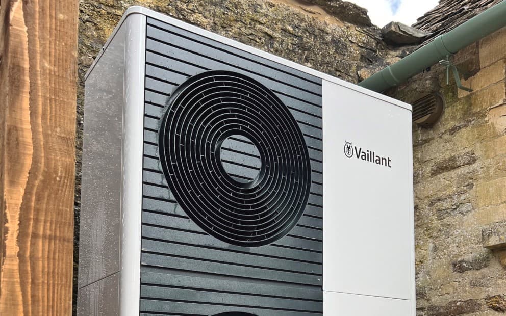 A close up shot of an aroTHERM plus heat pump unit from Vaillant in front of a stone wall.