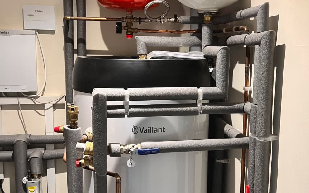 A Vaillant uniSTOR cylinder that has been plumbed in with numerous pipes surrounding it.