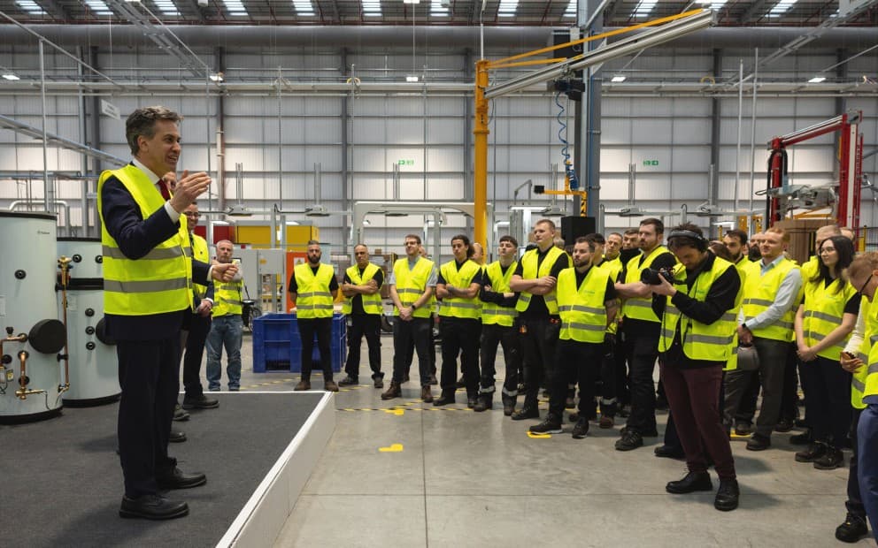 A group of individuals standing together inside a factory, surrounded by machinery and industrial equipment.