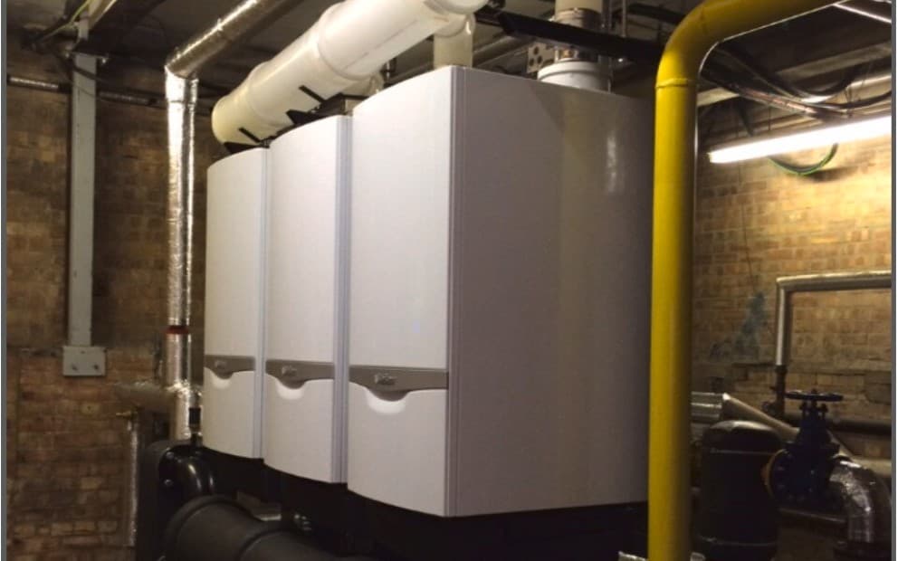 Three large industrial boilers installed within a commercial building's interior space.