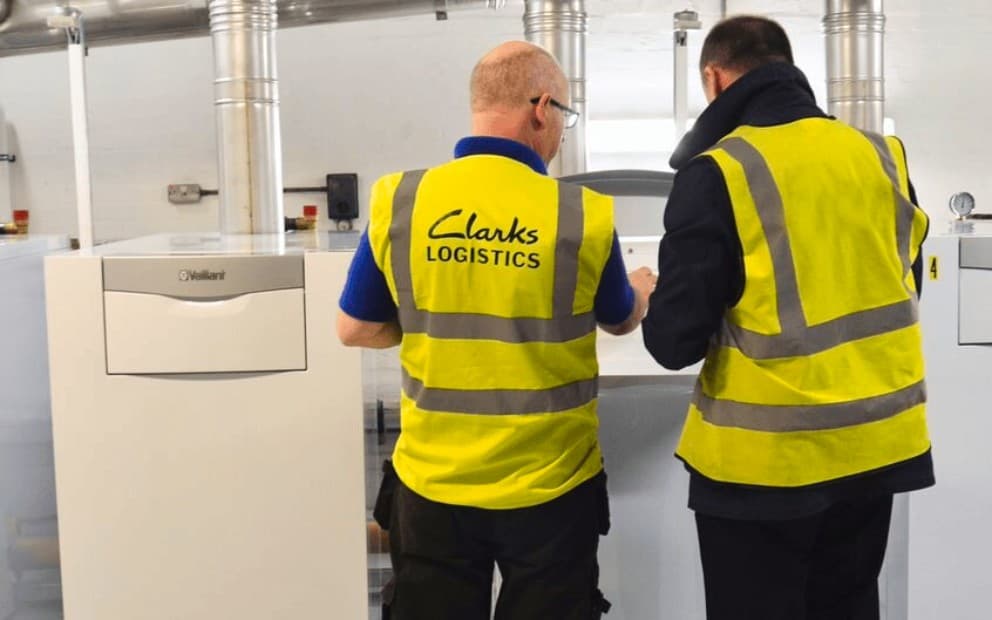 Two men in yellow vests examining a machine, focused on its components and functionality.
