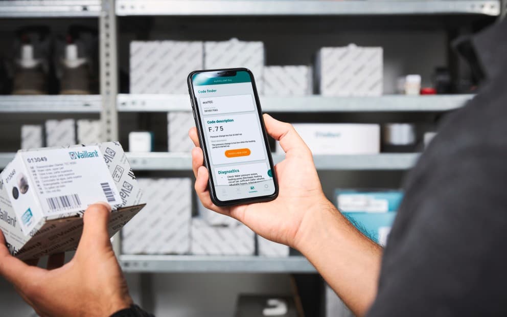 Person holding a mobile phone and holding a small box in the other hand.