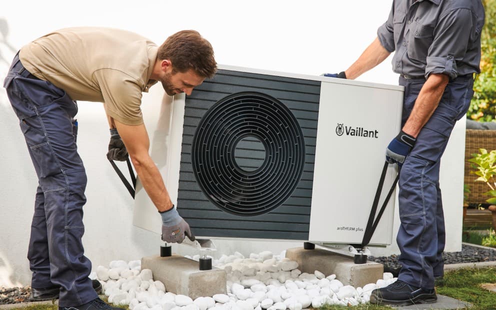 Two men installing a heat pump unit.