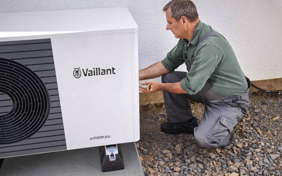 A heat pump installer doing work on a heat pump unit.