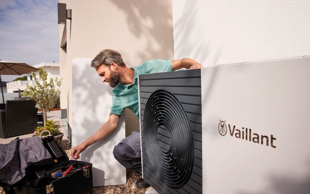 Man installing a heat pump unit. He is looking in his toolbox.