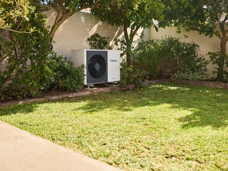 aroTHERM plus in a garden surrounding by bushes.