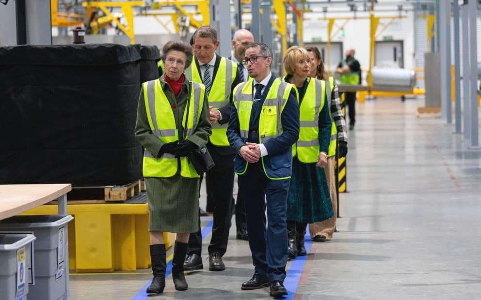 Joe Dunn, Henrik Hansen and HRH Princess Anne uncovered a plaque in a factory facility. There is a cylinder next to them.