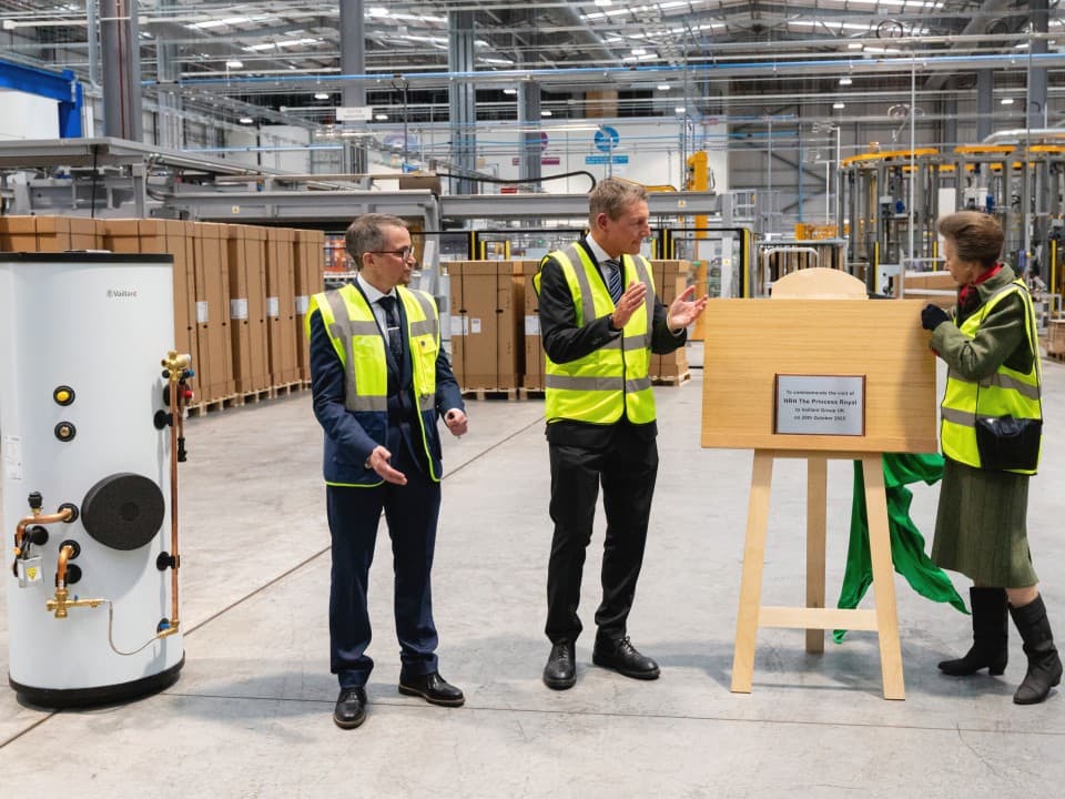 Joe Dunn, Henrik Hansen and HRH Princess Anne uncovered a plaque in a factory facility. There is a cylinder next to them.