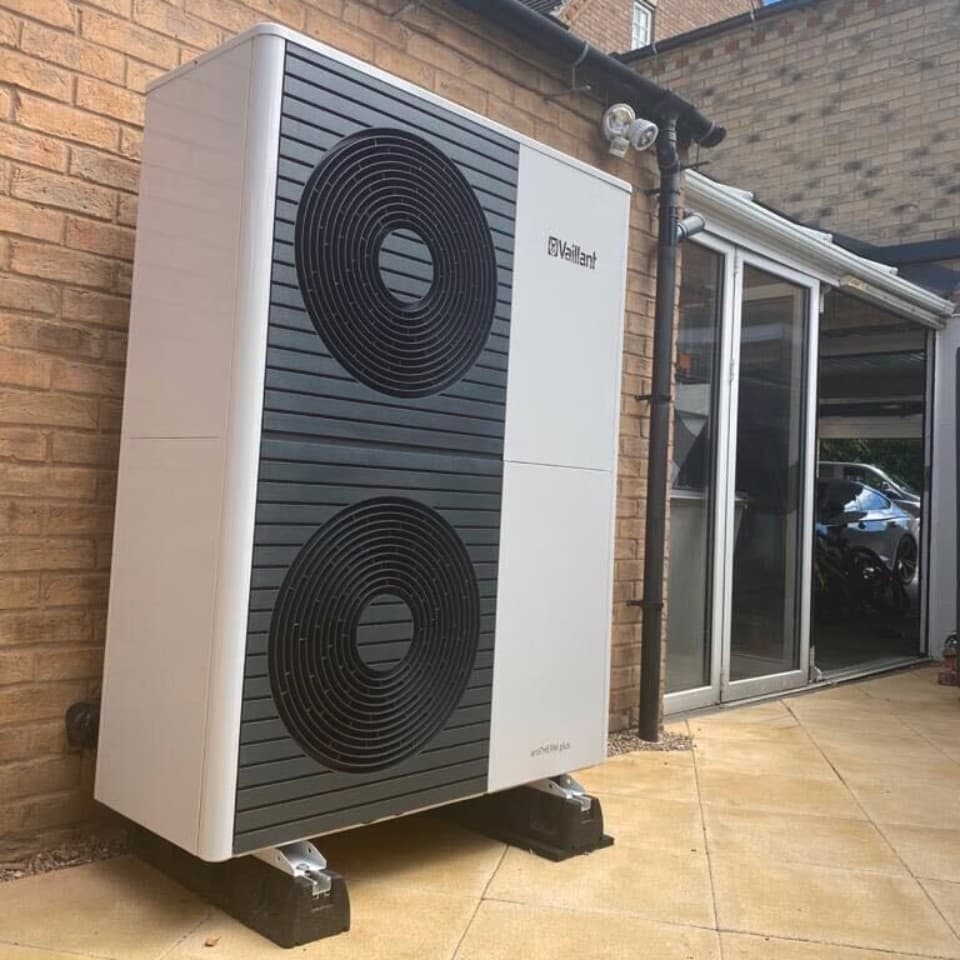 Double stacked heat pump in front of a brick wall and large patio door