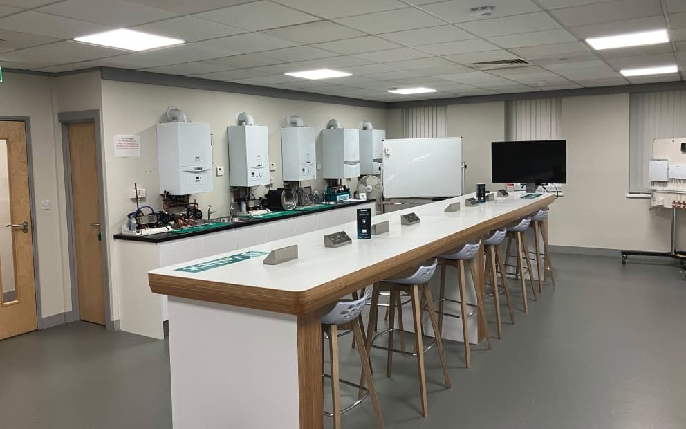 Inside a Vaillant training room with boilers and a desk and high chairs.