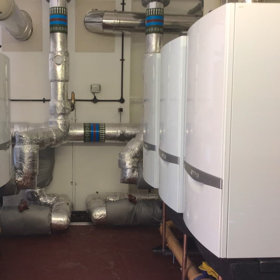 Side view of three commercial boilers in a industrial room