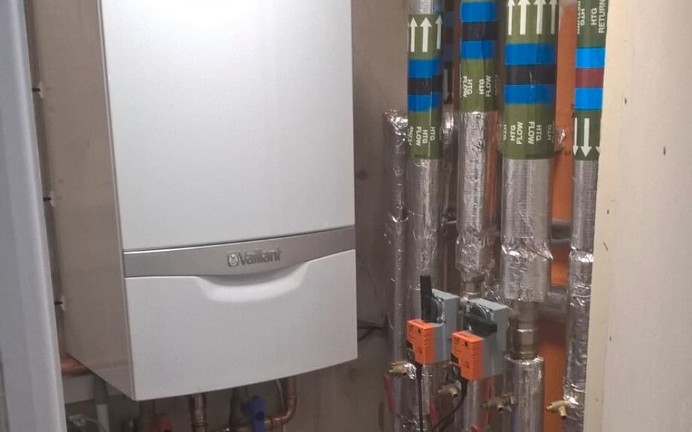Vaillant boiler in a small room with pipework running next to the boiler.