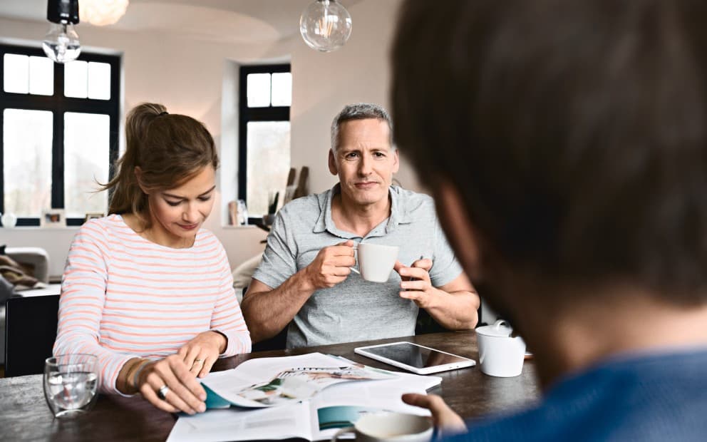 A man and woman sit at a table, whilst looking at a brochure.
