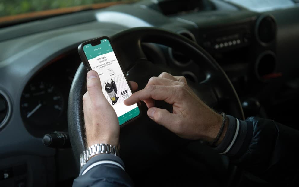 Someone sat in a van on their phone on the spareCHECK app.