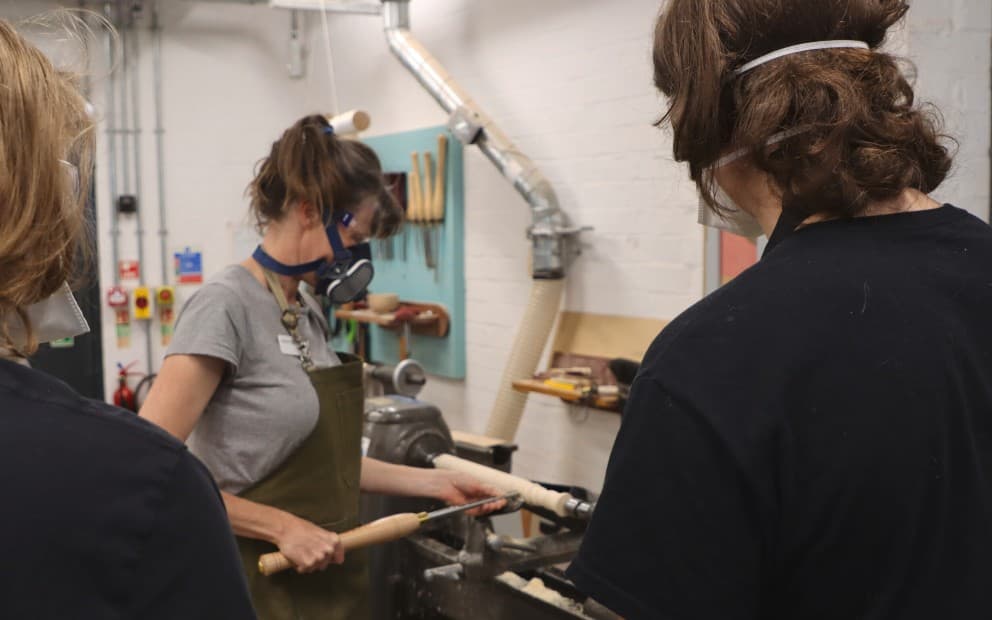 Students wearing masks doing work in a workshop environment.